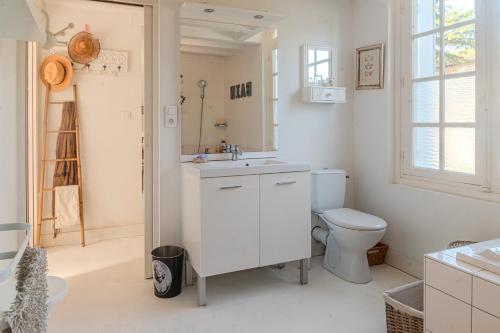 a white bathroom with a toilet and a sink at Villa au bord de la Charente in Jarnac