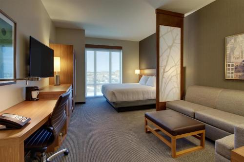 a hotel room with a bedroom with a bed and a couch at Hyatt Place Milwaukee Downtown in Milwaukee