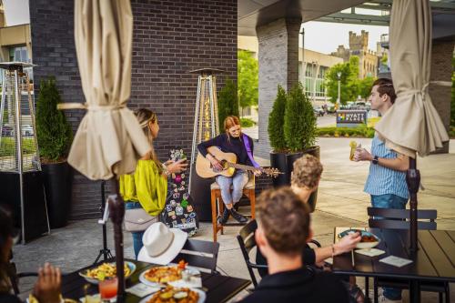 a group of people listening to a woman playing guitar at Hyatt Place Milwaukee Downtown in Milwaukee