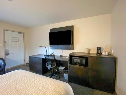a bedroom with a desk with a computer and a television at Rodeway Inn in Gaspé