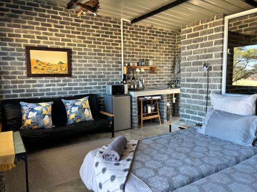 a bedroom with a bed and a brick wall at Northern Rock Accommodation in Otjiwarongo