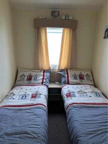 two beds in a small room with a window at Holiday home Golden Palm resort in Chapel Saint Leonards
