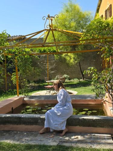 a woman sitting on a bench in a garden at Les Arcades Le Lion D'or in Buis-les-Baronnies
