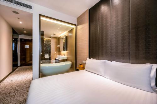 a bedroom with a bed and a bathroom with a tub at Dorsett Singapore - Newly Refurbished in Singapore