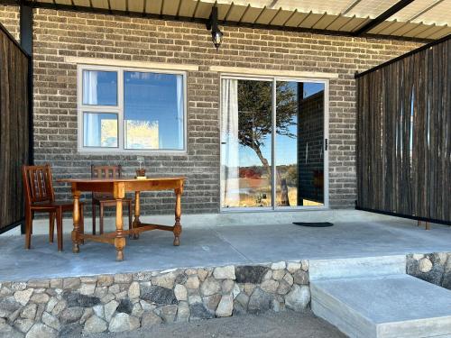 a patio with a wooden table and a chair at Northern Rock Accommodation in Otjiwarongo