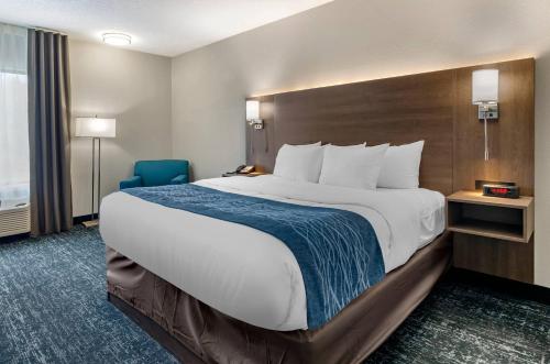 a hotel room with a large bed and a blue chair at Comfort Inn & Suites Troutville-Roanoke North in Troutville