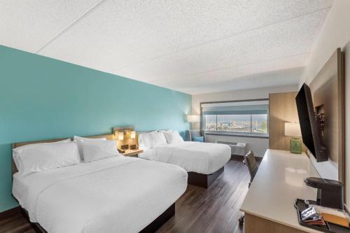 a hotel room with two beds and a flat screen tv at The Harborview on Lake Michigan, Ascend Hotel Collection in Port Washington