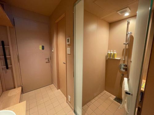 a bathroom with a shower and a glass door at toggle hotel suidobashi TOKYO in Tokyo