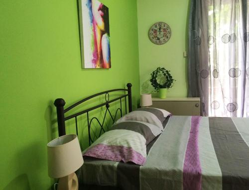een slaapkamer met een bed met groene muren bij Kalispera Apartment in Nafplio
