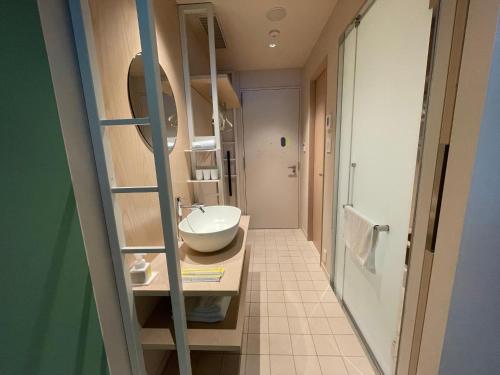 a small bathroom with a sink and a mirror at toggle hotel suidobashi TOKYO in Tokyo
