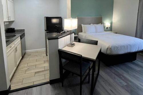 a hotel room with a bed and a small table and a room at MainStay Suites Sterling near Dulles Town Center in Sterling