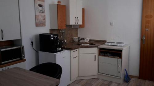 Elle comprend une petite cuisine avec des placards blancs et un évier. dans l'établissement FeWo Grunig, à Lahr/Schwarzwald