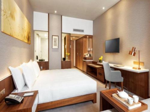 a hotel room with a large bed and a desk at Deacon House Wuxi in Wuxi
