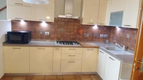 a kitchen with white cabinets and a microwave at QUEEN HOME S GIOVANNI ideal for families or large group in San Giovanni in Persiceto