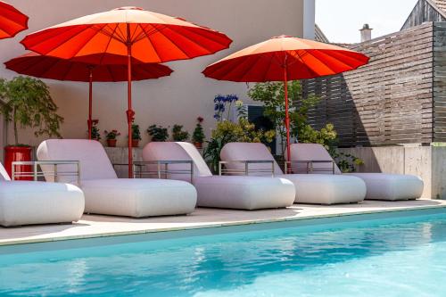 a group of chairs and umbrellas next to a swimming pool at Mörwald Gutshof in Feuersbrunn