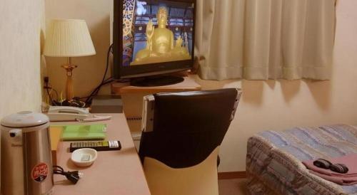 a room with a desk with a television and a chair at Chino Station Hotel in Chino