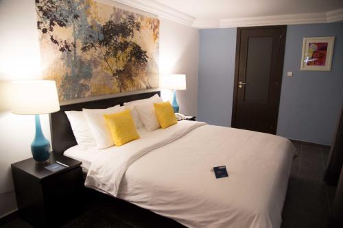 een slaapkamer met een groot wit bed met gele kussens bij Hôtel Semiramis City Center in Nouakchott