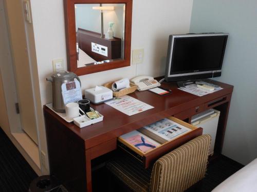 a desk with a computer and a television on it at Paradis Inn Sagamihara in Sagamihara