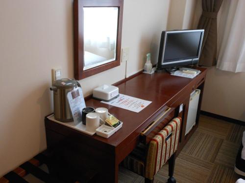 a desk with a computer and a television on it at Paradis Inn Sagamihara in Sagamihara