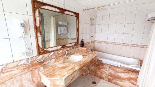 a bathroom with a sink and a mirror and a tub at Hi-YES HOTEL TAOYUAN in Zhongli