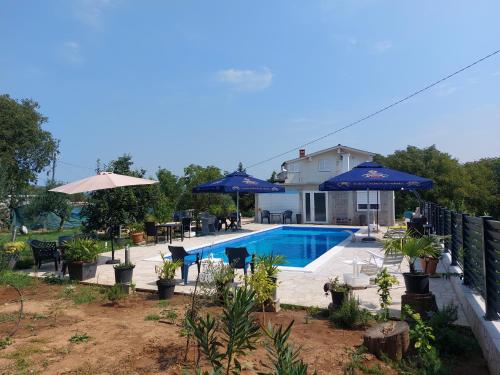 a swimming pool with umbrellas and a house at Unterkunft Dalmatin in Dračevo