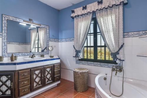 bagno con vasca, lavandino e finestra di Cortijo La Dehesa del Pilar a Setenil