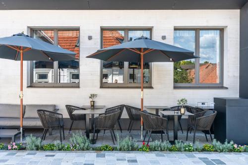 two tables and chairs with umbrellas in front of a building at MÖRWALD Relais & Châteaux Hotel am Wagram in Feuersbrunn