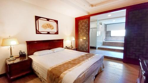 a bedroom with a large bed and a hallway at Hi-YES HOTEL TAOYUAN in Zhongli
