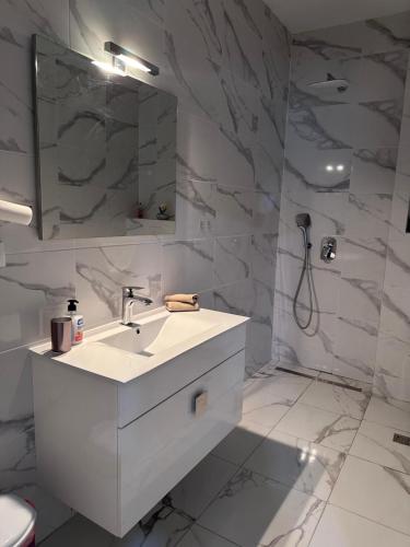 a white bathroom with a sink and a shower at Apartmani Novak in Mostar