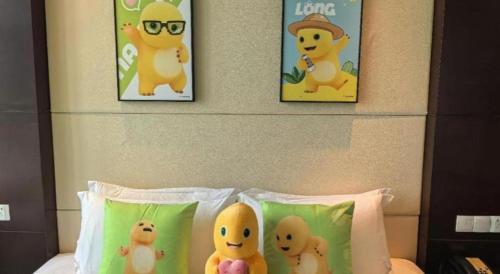 three pikachu posters on a wall above a bed with pillows at Suzhou Qingshan Conference Center in Suzhou