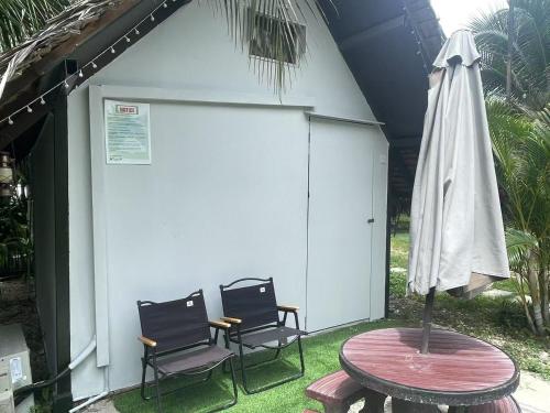 a patio with two chairs and a table and an umbrella at TK Coconut Camping in Tanjung Karang