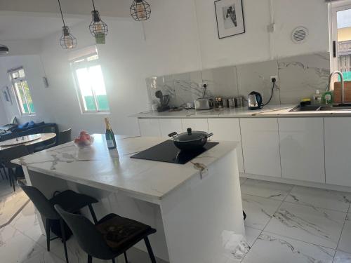 Apartment in villa with sea view في Calodyne: مطبخ أبيض مع منضدة عليها صحن