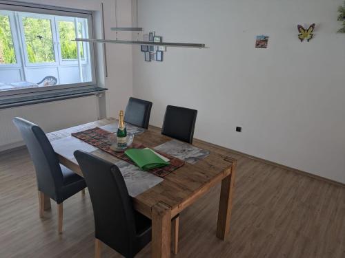 a dining room table with chairs and a bottle of wine at Spacious and Luminous Apartment in a Bungalow in Züsch