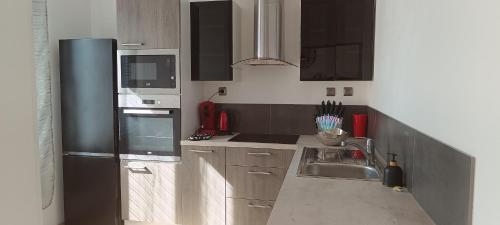 cocina con fregadero y nevera negra en Chez MaLouNa - 15 min de la Baie de Somme, en Friville-Escarbotin