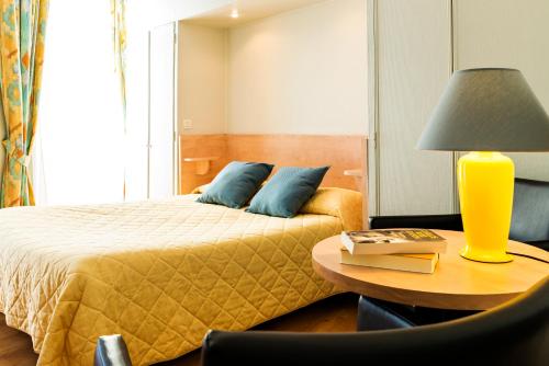 a bedroom with a bed and a table with a lamp at Hôtel Panoramic in Luchon