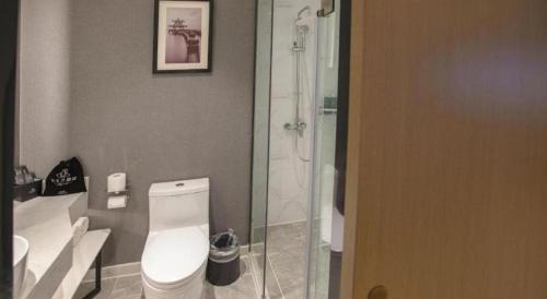 a bathroom with a white toilet and a shower at Magnotel Hotel Dongxing Guomen Port in Fangcheng