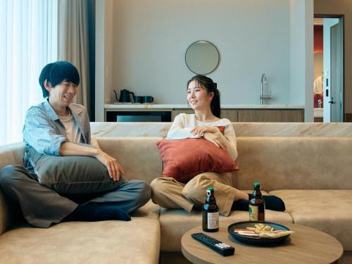 a man and a woman sitting on a couch at FAV LUX Sapporo Susukino in Sapporo