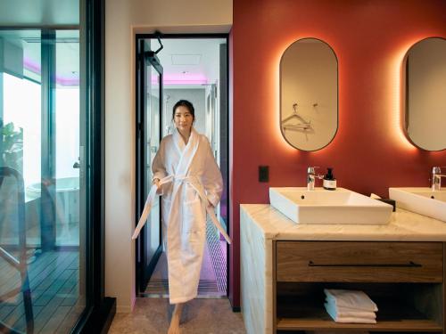 a woman standing in a bathroom with a mirror at FAV LUX Sapporo Susukino in Sapporo