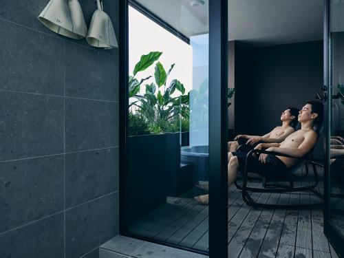 two men sitting in a chair in a bathroom at FAV LUX Sapporo Susukino in Sapporo