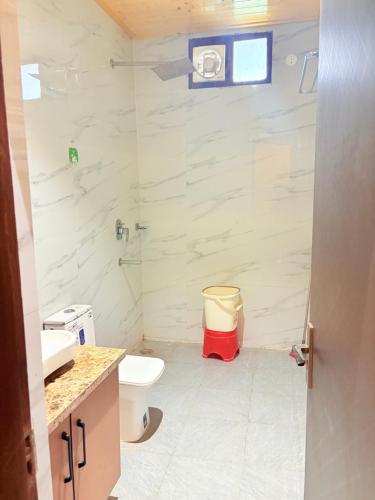 a white bathroom with a toilet and a shower at 4BHK Greenwood Farm And Lawn -Bijwasan I Delhi-Gurgaon Border I 87oo2o5865 in Gurgaon