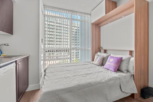 a bedroom with a bed with a large window at Charming Studio in Downtown Toronto in Toronto