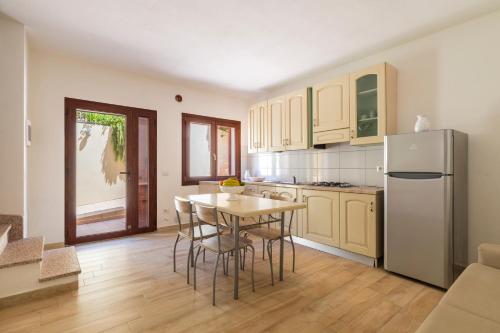 a kitchen with a table with chairs and a refrigerator at Corte di Gallura in Budoni
