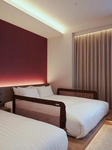 a hotel room with two beds and a window at FAV LUX Sapporo Susukino in Sapporo