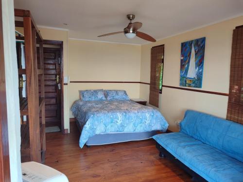 a bedroom with a bed and a blue couch at Vila do Monte, Villa #8, Ponta Mamoli in Ponta Mamoli