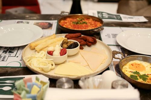 a table with a plate of food and other foods at AXU AIRPORT HOTEL in Arnavutköy