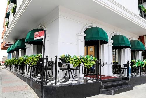 a building with tables and chairs and green umbrellas at AXU AIRPORT HOTEL in Arnavutköy