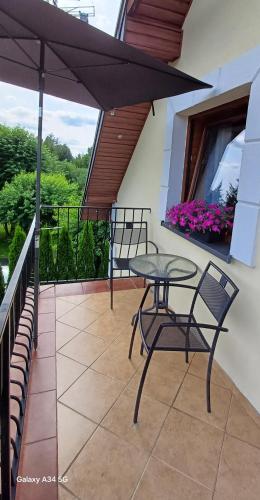 a patio with a table and chairs and an umbrella at Willa Zielone Wzgórze in Okuninka