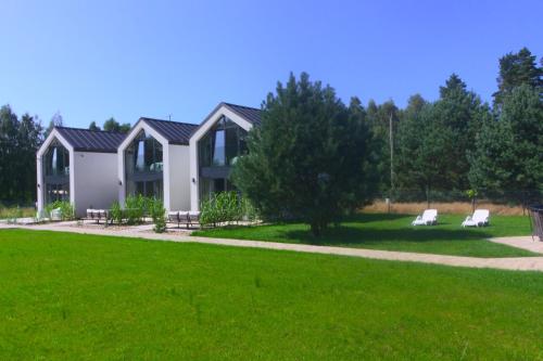 a house with two white chairs in a yard at NATURA APARTAMENTY Era in Ulinia