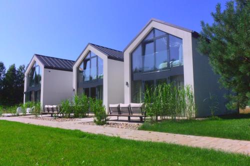 a house with glass windows on a green lawn at NATURA APARTAMENTY Era in Ulinia