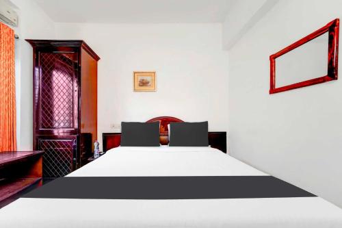a bedroom with a large white bed with two chairs at Hotel O Chalai Bazaar Near Railway Station in Trivandrum